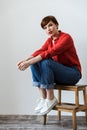 Image of brunette woman looking at camera while sitting on wooden stand