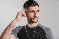 Image of brutal unshaven sportsman posing and using earphones