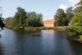 Image of a building and a lake with ducks surrounded by nature reflecting serenity