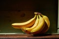 Image of bunch of ripe yellow bananas on wooden background, bright sunlight, harvest in wooden box