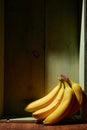 Image of bunch of ripe yellow bananas on wooden background, bright sunlight, harvest in wooden box