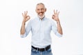 Image of businessman showing okay sign, ok gesture, approve, recommend something awesome, standing against white Royalty Free Stock Photo