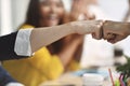 Image of 2 businesspersons fist-bumping in agreement at a meeting