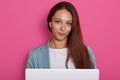 Image of businesswoman sitting in front laptop, attractive female posing isolated over pink studio backgroud. Young pretty woman Royalty Free Stock Photo