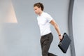 Image of Calm curly business man with briefcase walking