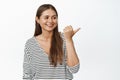 Image of candid happy woman pointing finger and looking right at advertisement, smiling and laughing over logo banner