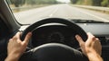 Hands on the wheel controlling the car in motion on the open road landscape Royalty Free Stock Photo