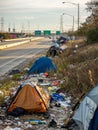 The image captures a roadside encampment with several tents. There is a significant amount of litter and debris