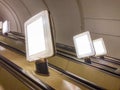 Image captures view from above of an ascending, empty escalator with a metallic finish Lighting casts shadows and