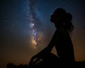 Silhouette of a woman in thoughtful repose under the Milky Way\'s celestial river