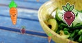 Image of carrot and beetroot icons falling over bowl of fruit salad on blue wooden table Royalty Free Stock Photo