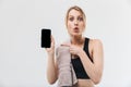 Image of caucasian blond woman 20s dressed in sportswear with towel over neck using smartphone during workout in gym Royalty Free Stock Photo