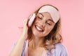 Image of caucasian cheerful woman smiling while using cosmetic sponge