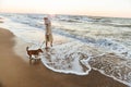 Image of caucasian woman 20s in summer straw hat, walking by seaside with her dog