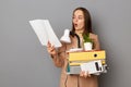 Image of Caucasian woman worker holding office cardboard, being fired from business job, looks scared and shocked, has surprise Royalty Free Stock Photo