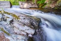 Cement dam funneling river with large outcropping of stone covered in moss