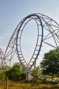 Centered shot of a blue rollercoaster surrounded by trees on a clear grayish day