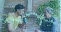 Image of changing numbers and graphs over diverse son talking with father while drinking coffee Royalty Free Stock Photo