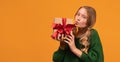 Image of charming blonde girl 12-14 years old holding present box with red bow. Mock up copy space