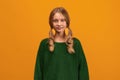 Image of charming blonde teen smiling and looking at camera. Studio shot, yellow background. Facial expression concept