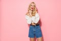Image of charming blonde woman with long curly hair wearing trendy clothes smiling and posing at camera Royalty Free Stock Photo