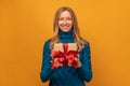 Image of charming young woman smiling and holding gift with red ribbon. New Year, Birthday, Holiday concept