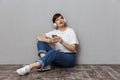 Image of young woman using cellphone and headphones sitting on floor Royalty Free Stock Photo