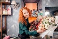 Cheeful young florist standing next to bouquets of vernal flowers in shop