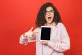 Image of cheerful amazed young curly caucasian woman showing display of tablet computer Royalty Free Stock Photo