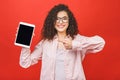 Image of cheerful amazed young curly caucasian woman showing display of tablet computer Royalty Free Stock Photo