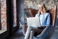 Image of cheerful office woman with blond hair in business wear sitting on chair and working with laptop office.