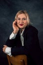 Image of a cheerful office woman with long white hair in business clothes sitting on a chair and looking away Royalty Free Stock Photo