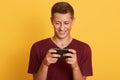 Image of cheerful sincere good looking guy playing games, using his smartphone, looking attentively at screen, having pleasant Royalty Free Stock Photo