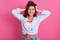 Image of cheerful young beautiful woman standing  over pink background in studio, keeping her hands on head, laughing Royalty Free Stock Photo