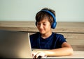 Image of cheerful young caucasian boy  wearing headset using laptop with smiling happy face. Online learning and entertainment for Royalty Free Stock Photo