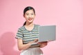 Image of cheerful young woman standing isolated over pink background using laptop computer. Looking camera Royalty Free Stock Photo