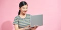 Image of cheerful young woman standing isolated over pink background using laptop computer. Looking camera Royalty Free Stock Photo