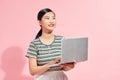 Image of cheerful young woman standing isolated over pink background using laptop computer. Looking camera Royalty Free Stock Photo
