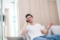 Young man indoors at home on sofa using laptop computer talking by mobile phone Royalty Free Stock Photo