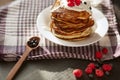 Image of cheese pancakes with sour cream and fresh berries, blackberry jam in wooden spoon, whipped cream on muffins top, served Royalty Free Stock Photo