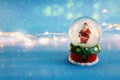 Image of christmas snow glass ball with santa claus in front of glitter blue background Royalty Free Stock Photo