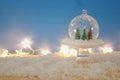 image of christmas trees inside glass ball over snowy wooden table.