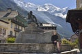 Image of city square with statue and a traveler. Mont Blanc in background. Royalty Free Stock Photo