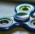 Image of close up of blue metallic fidget spinner on black background Royalty Free Stock Photo