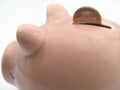Image of a close up of a piggy bank, with a 1 euro coin falling into the slot Royalty Free Stock Photo