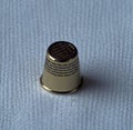 Image of close up of silver thimble on blue fabric background Royalty Free Stock Photo