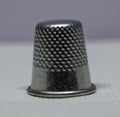 Image of close up of silver thimble on grey patterned fabric background