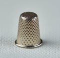 Image of close up of silver thimble on grey patterned fabric background