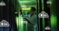 Image of clouds with uploading over asian man working in server room Royalty Free Stock Photo