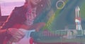 Image of coloured light waves over caucasian female guitarist playing red electric guitar